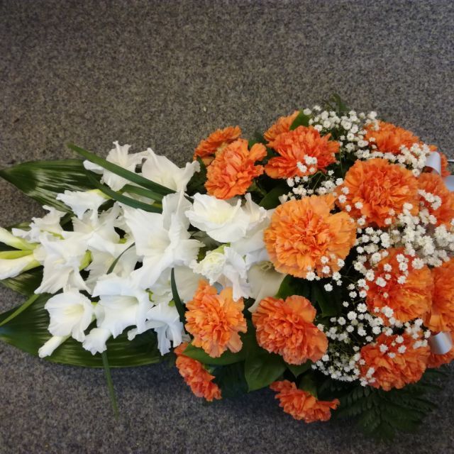 Oransseista ja valkoisista kukista sidottu hautajaiskimppu