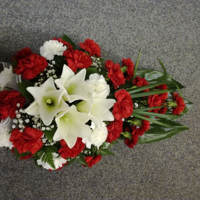 Valkoisista ja punaisista kukista sidottu hautajaislaite