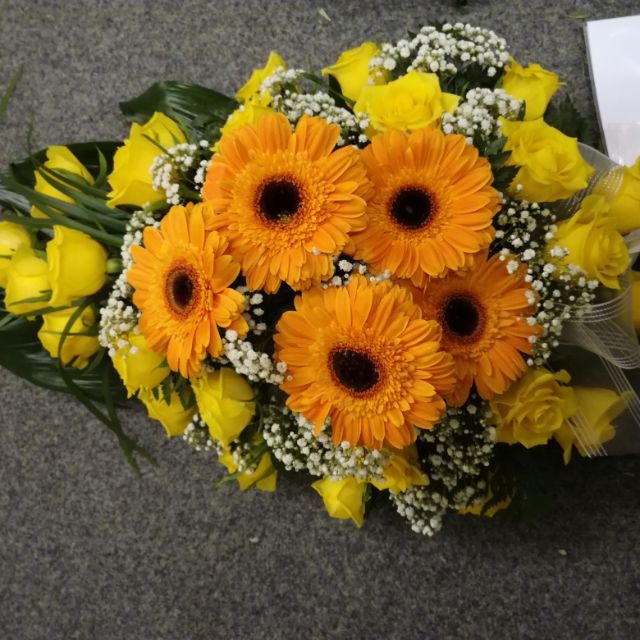 Hautajaiskimppu oransseilla ja keltaisilla kukilla